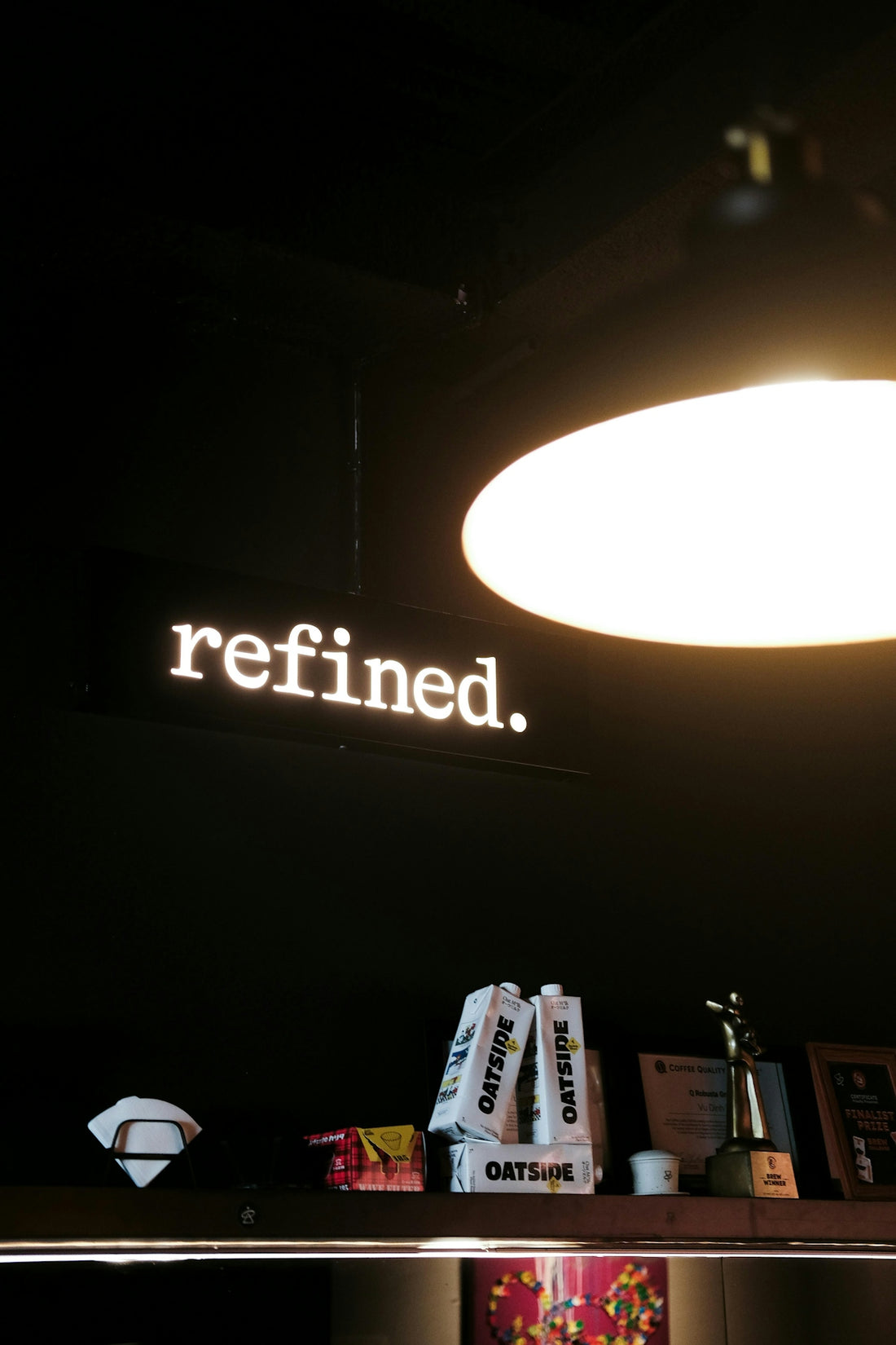 A neon sign that says refined above shelves.