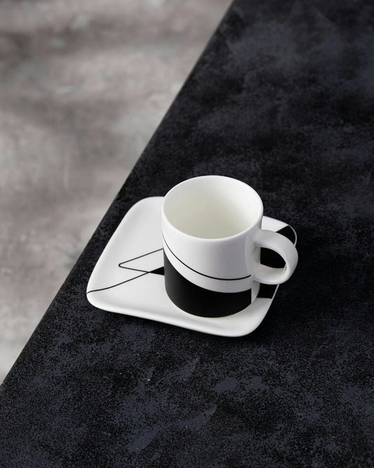 Modern white coffee cup and saucer on dark textured surface.