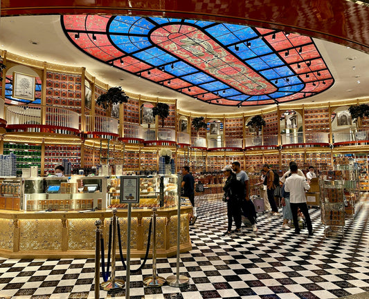 Luxurious store interior with ornate stained-glass ceiling and checkered floor.
