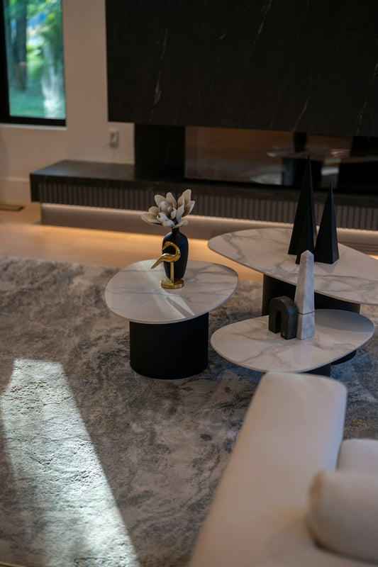 Three tiered marble coffee tables with decorative objects in a modern living room