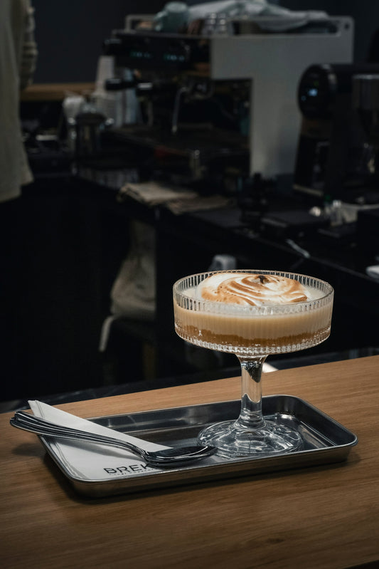 A layered dessert with toasted meringue in a glass on a metal tray